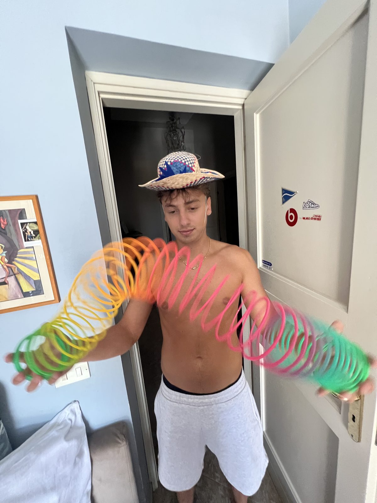 Cappello di paglia, torso nudo e una molla arcobaleno tesa tra le mani
